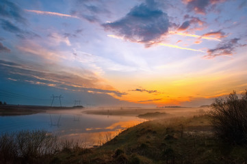 View of nature in the fog at sunset. Dramatic clouds in the background of the misty river. Mysterious natural landscape