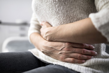 Naklejka premium Tired exhausted woman with stomach issues at home on a couch, being sick, pregnant.