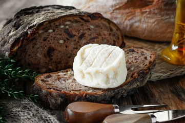 Soft delicious round cheese with white mold on a piece of craft bread with olive oil