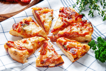 Slices of pizza with mozzarella and spicy salami on a plate on the table with decorations. Traditional Neapolitan Italian fast food