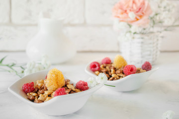 Organic granola with raspberries for Breakfast in a white porcelain Cup on a light background