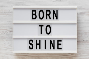 'Born to shine' words on a modern board on a white wooden surface, top view. Overhead, from above, flat lay. Close-up.