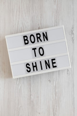 'Born to shine' words on a lightbox on a white wooden background, top view. Overhead, from above, flat lay. Closeup.