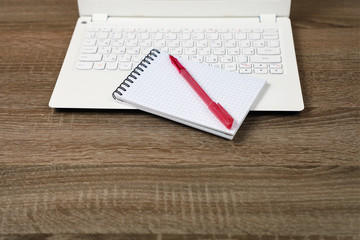 White laptop, Notepad, pen, on a dark wooden table, layout.