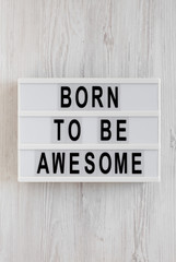 'Born to be awesome' words on a modern board on a white wooden background, top view. Overhead, from above, flat lay. Close-up.