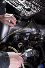 Fototapeta na wymiar Car services. Hands of a mechanic with a tool. Car engine repair.