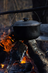 Cooking in field conditions, boiling pot at the campfire on picnic. Filtered image:cross processed vintage effect.