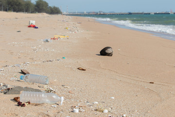 The plastic bottle rubbish on the sand at the beach, with sea water and industrial bridges far away It's a marine environmental problem.