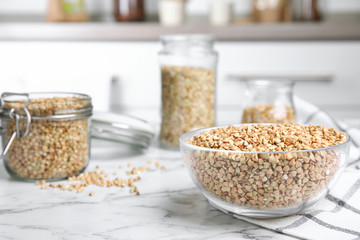 Uncooked green buckwheat grains on white marble table