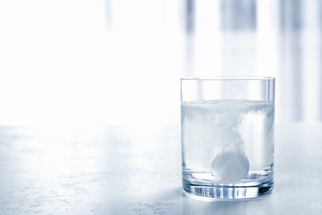 Glass of water with effervescent tablet on light table indoors, space for text