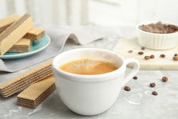 Fotobehang Delicious wafers and cup of coffee for breakfast on grey marble table © New Africa