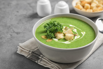 Tasty kale soup with croutons on grey table
