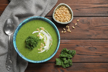 Tasty kale soup served on wooden table, flat lay