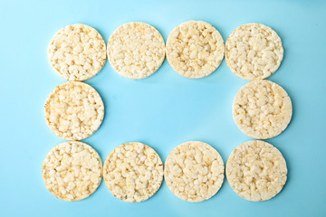 Frame made of puffed rice cakes on light blue background, flat lay. Space for text