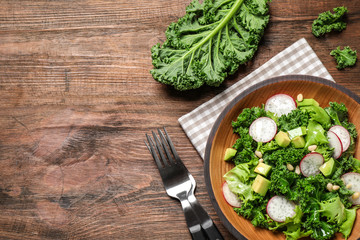 Delicious kale salad on wooden table, flat lay. Space for text