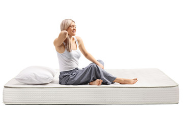 Young woman sitting on a bed mattress with painful neck