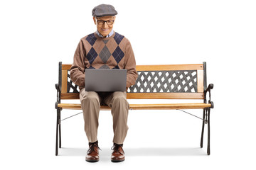 Senior man sitting on a bench and using a laptop computer