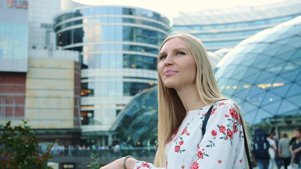 Fototapeta na wymiar Amazed woman in modern city. Young lady in elegant outfit admiring view in astonishment while standing on background of futuristic building on street of modern city.