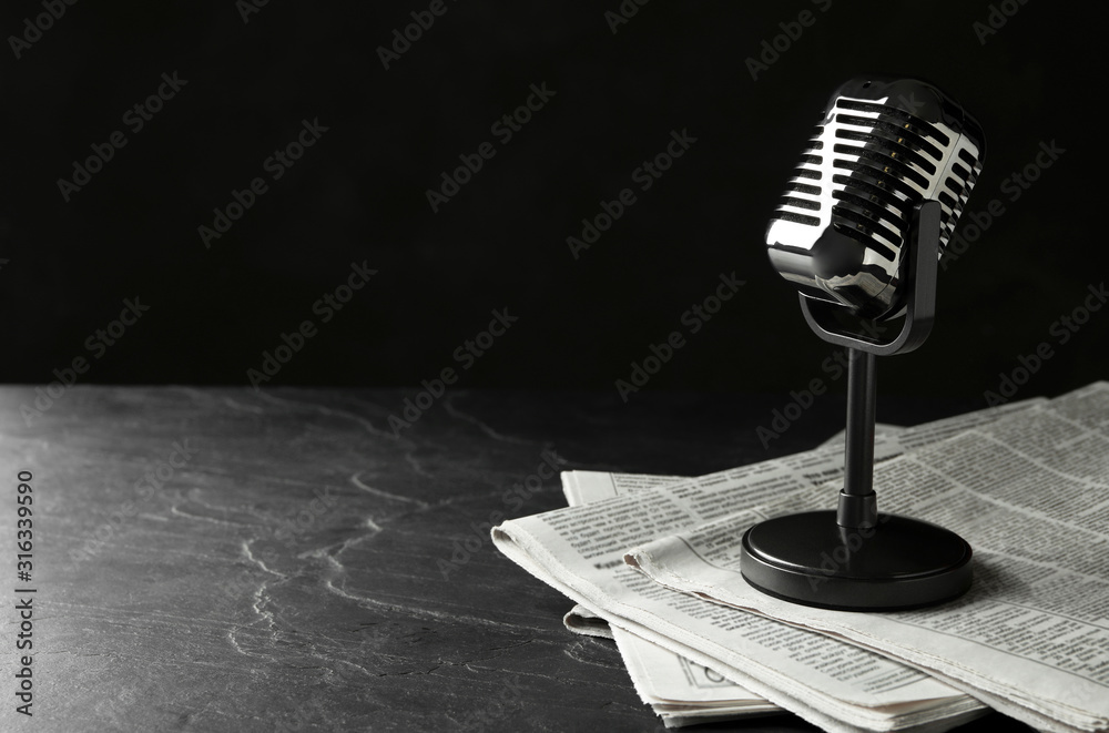 Wall mural newspapers and vintage microphone on dark stone table, space for text. journalist's work