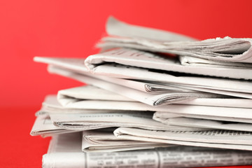 Stack of newspapers on red background, closeup. Journalist's work