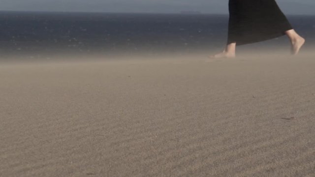 Pies de mujer caminando por la arena con viento HD
