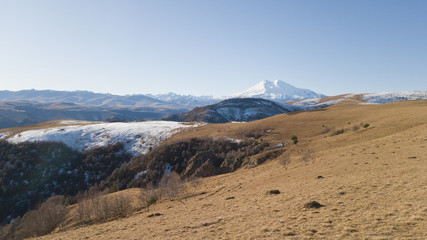 Spring landscape with views of a dry arid high-altitude field and mount Elbrus in the distance. Travel to Russia and the Caucasus