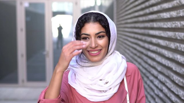 Young Muslim woman wearing hijab headscarf walking in the city center.