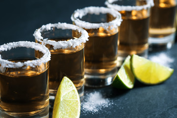 Mexican Tequila shots, lime slices and salt on grey table, closeup