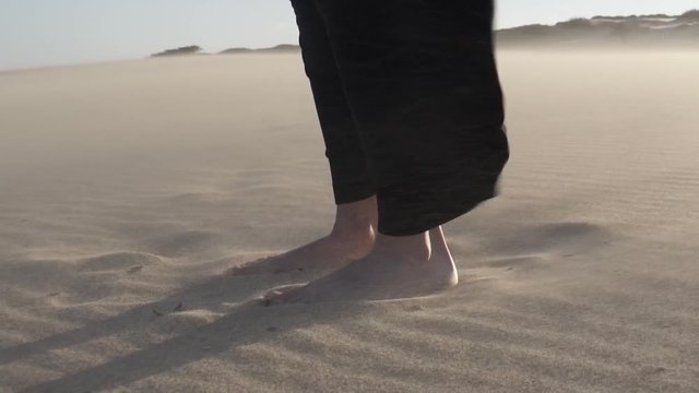 Pies de mujer en la arena con viento HD