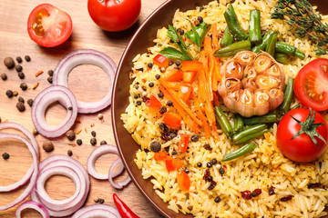 Tasty rice pilaf with vegetables on wooden table, flat lay