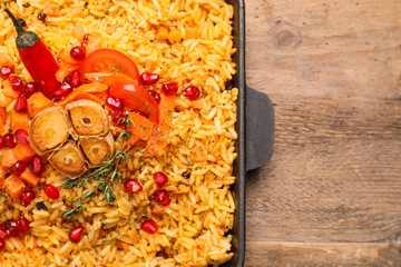Tasty rice pilaf with vegetables on wooden table, top view