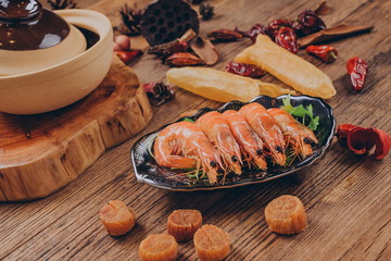 Five shrimp, already cooked, on a black plate, with a slice of vanilla on the side.