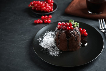 Delicious warm chocolate lava cake with mint and berries on dark grey table