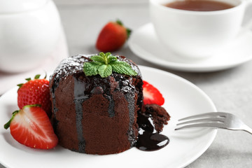 Delicious warm chocolate lava cake with mint and strawberries on table, closeup