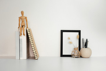 Desktop table with book decorate, frame and jar of pen on white table and white background.