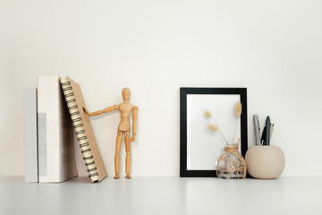 Desktop table with book decorate, frame and jar of pen on white table and white background.