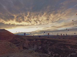Colorful hot air balloons flying at the sunrise  with rocky landscape in Cappadocia, Turkey