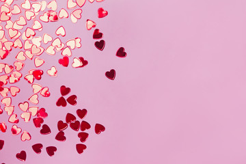 Small red heart shaped confetti on pink background