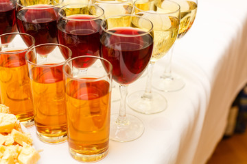 Wineglasses with red and white wine in a row. Buffet table with drinks. Wine and juice for celebration, party, entertainment. Wine tasting, nightlife