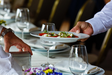 Man in restaurant holding white plate with vegetarian organic salad. Vegan meal, healthy food