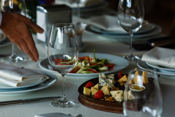 Сheeseboard in a restaurant with variety types of cheese. Cheddar, Edam, Gouda, Roquefort, Gorgonzola with strawberry and walnut. Empty wineglass on a table. Cheese tasting