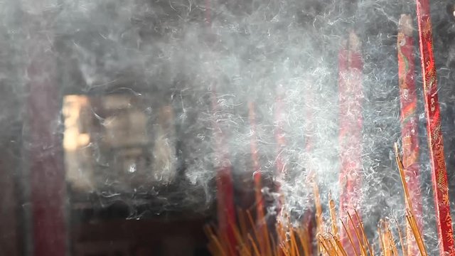 Incense burning inside a temple in Vietnam. The rising smoke forms interesting patterns as they rise into the air.