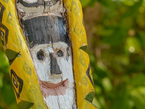 view of old traditional Moken Spirit Pole wood craft design like face of human with green nature blurred backgroud, The Moken take spirit pole for navigate around island, Surin island, Thailand.