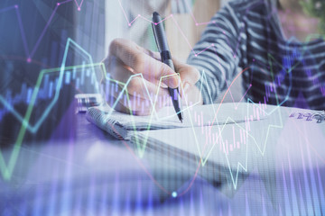 Fototapeta na wymiar Financial forex graph drawn over hands taking notes background. Concept of research. Double exposure