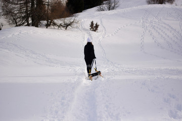 The girl with the sled goes up the mountain