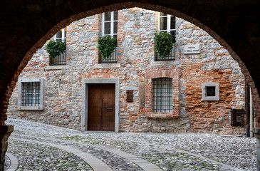 Medieval street arch under an ancient brick wall of a building facade in the town of Cividale del Friuli. Udine, Friuli Venezia Giulia, Italy