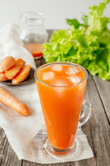 Delicious and fresh carrot juice with mint and lettuce leaves. Chilled vegetable smoothie with ice in a glass glass. Close up