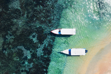 Boats on the water surface and beach from top view. Azure water background from drone. Summer...