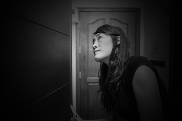 Scared woman looking on closet searching for something wrong in white tone