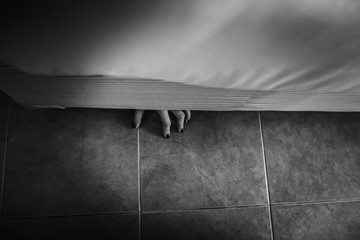 Horror shoot, hand of woman out from under the bed in whit e tone - obrazy, fototapety, plakaty